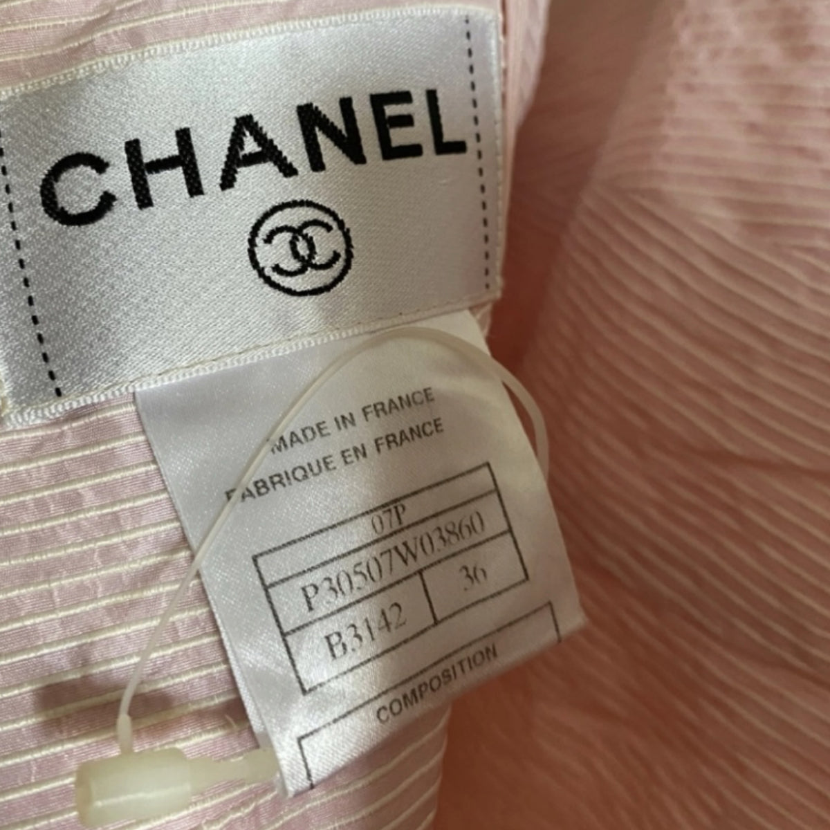 Fivedotsvintage Chanel dress interior label showing brand logo and production details on pastel pink textured fabric